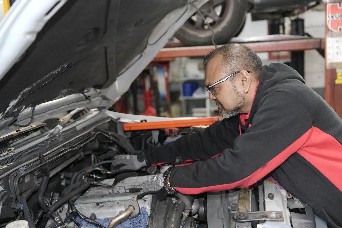 A mechanic working in the engine bay at HM Motors, New Lynn