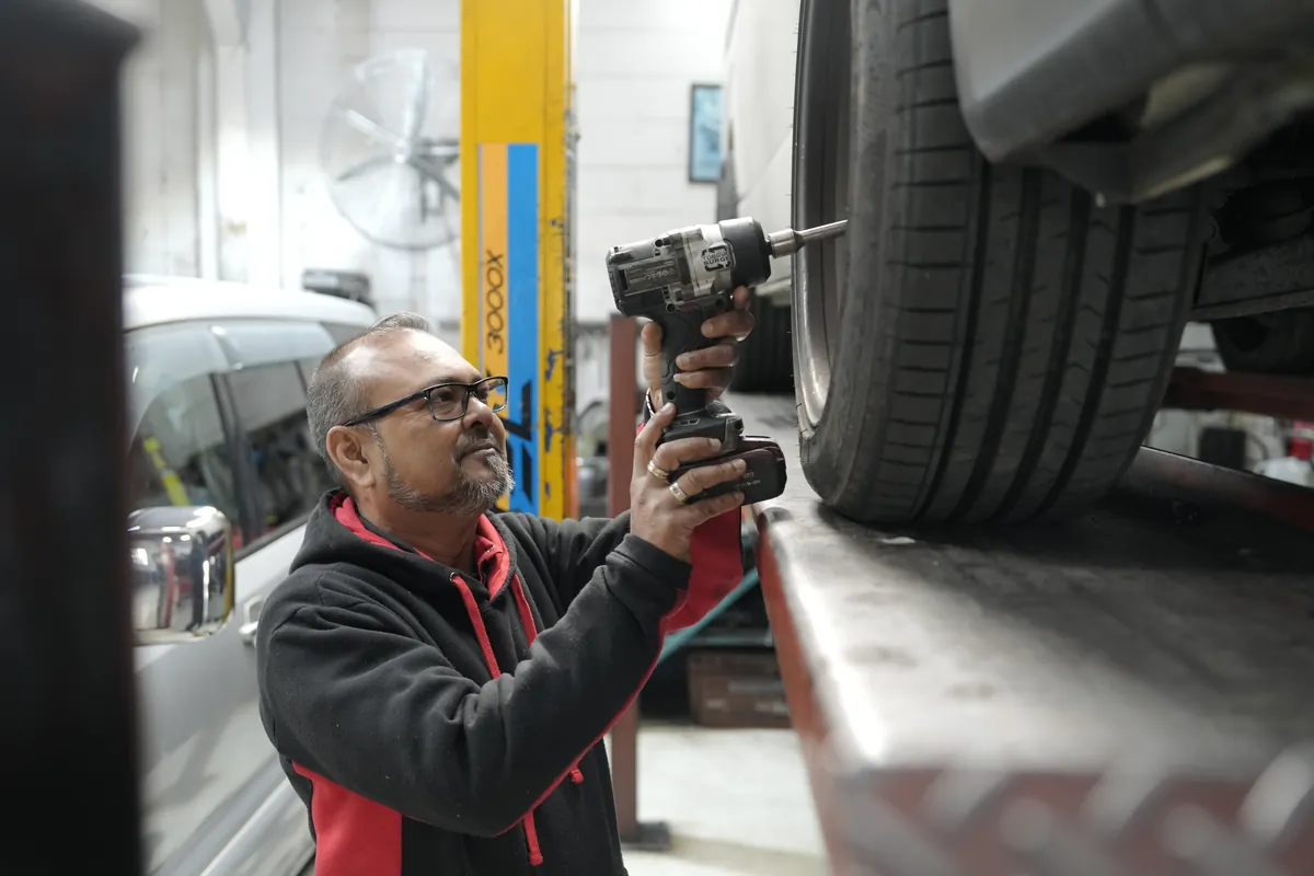 Removing a wheel with an impact wrench at HM Motors, New Lynn