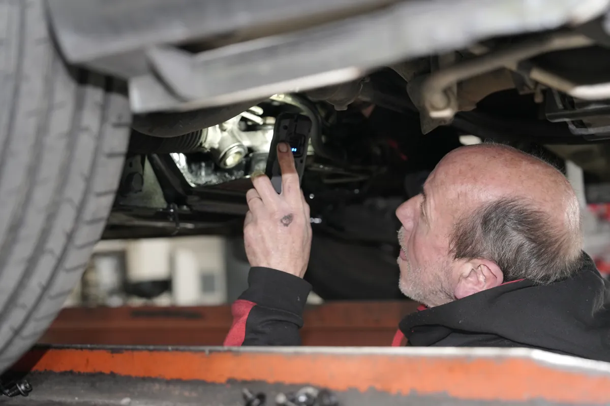 A mechanic inspecting the underside of a vehicle during a WOF at HM Motors, New Lynn